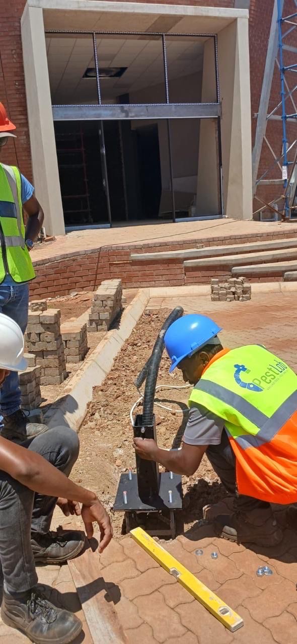 Workers installing pole base on brickwork site