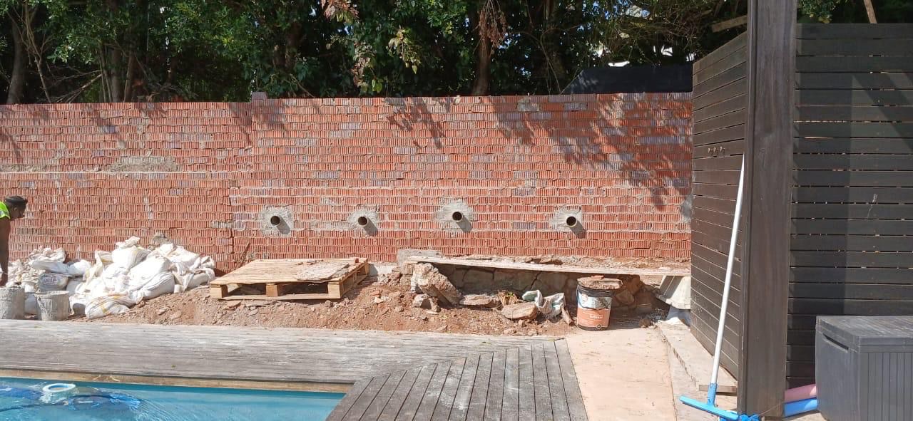 Brick retaining wall with drainage holes near pool