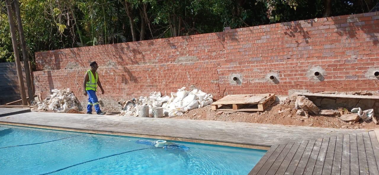 Worker at pool with brick retaining wall construction