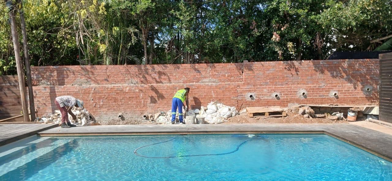 Workers at pool with brick retaining wall