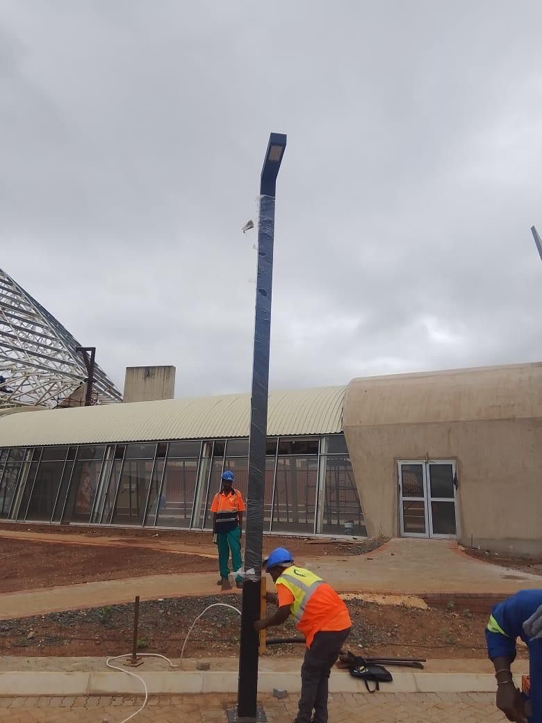 Workers installing light pole on site