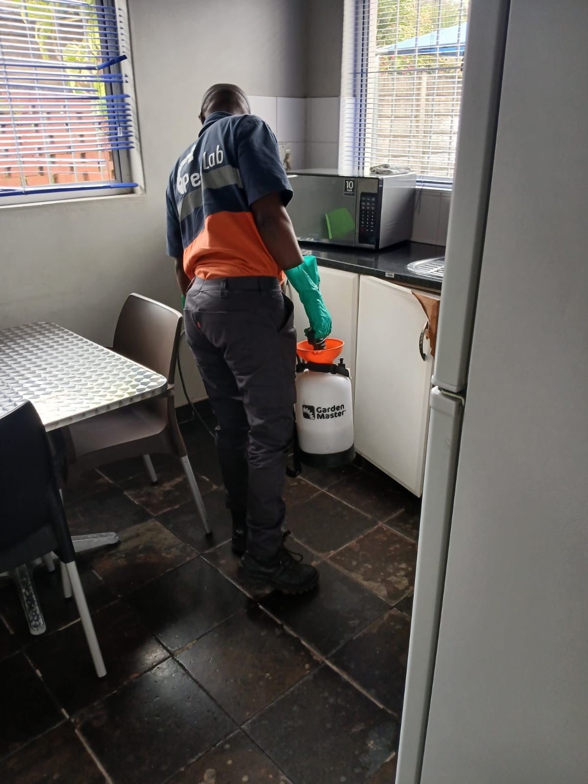 Pest Lab technician spraying in kitchen with pump